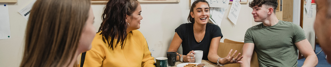 Group of young people talking over tea and biscuits