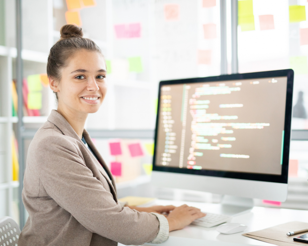 Female ICT professional sitting by her desk analysing coded data on computer screen
