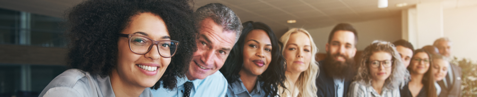 Smiling, diverse corporate colleagues standing together in a bright modern office, representing teamwork, apprenticeships, and workforce upskilling.